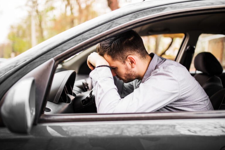 young man sitting in car very upset and stressed after hard fail