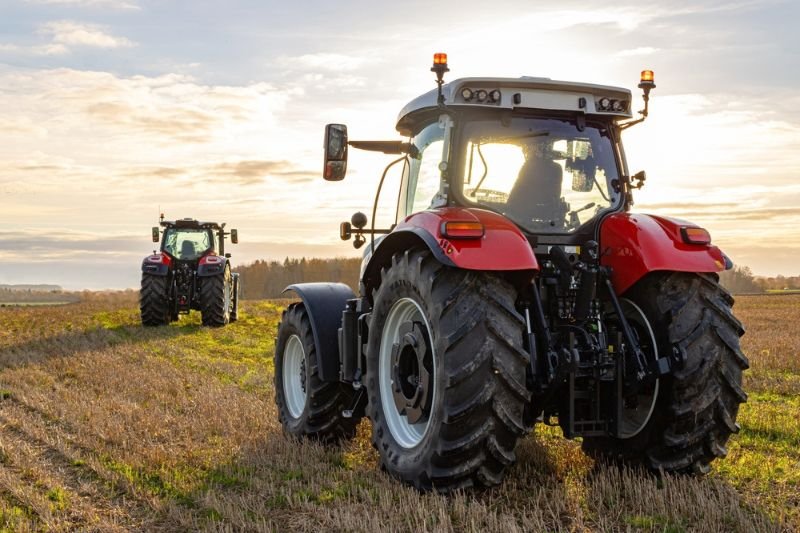 trator agricola durante operacao em lavoura com horizonte ao fundo
